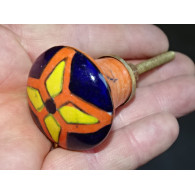 Botón naranja en forma de pera y flor amarilla y ultramar.